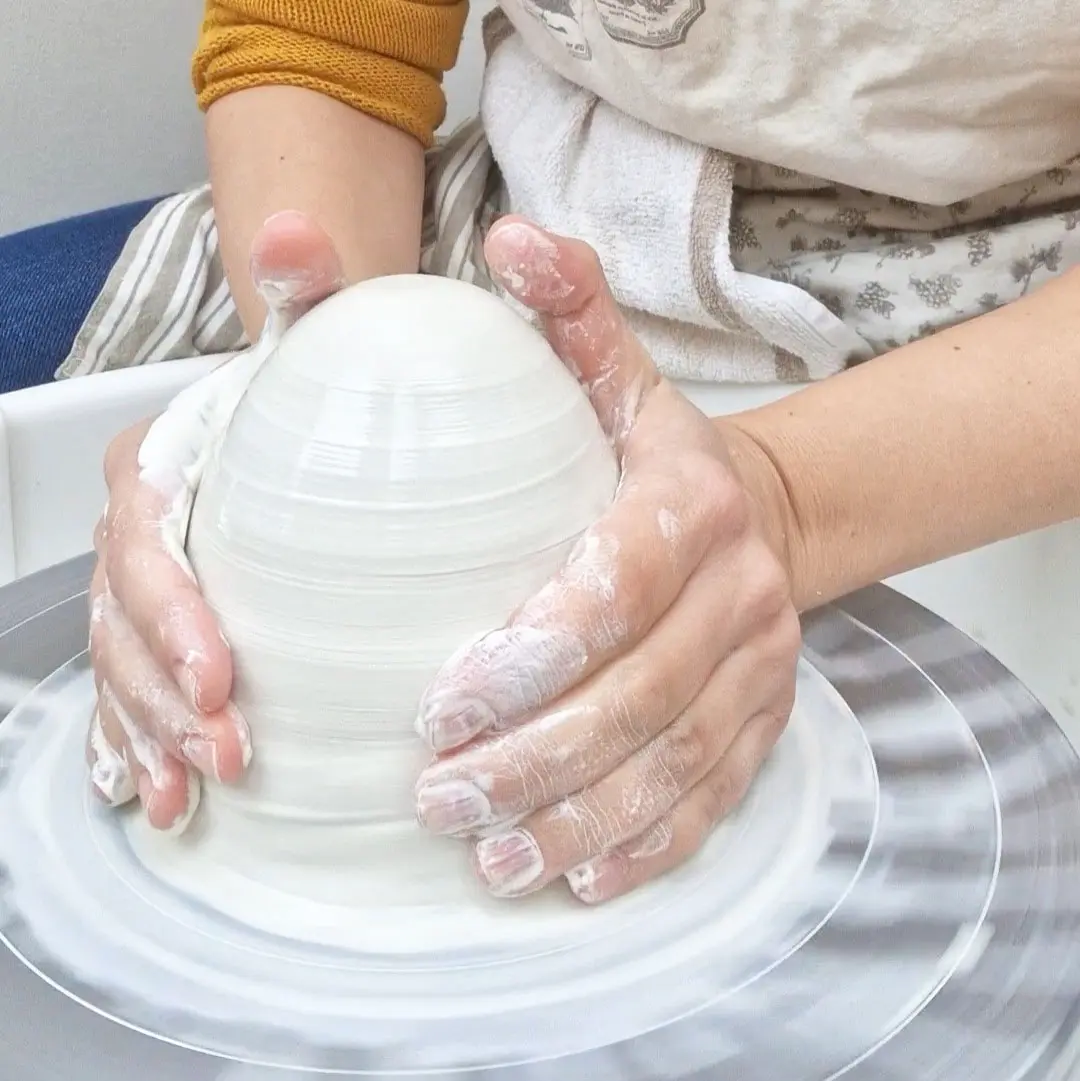 Hands working with clay during a pottery class