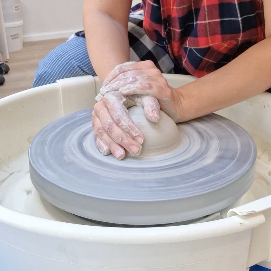 Hands centering clay on a pottery wheel
