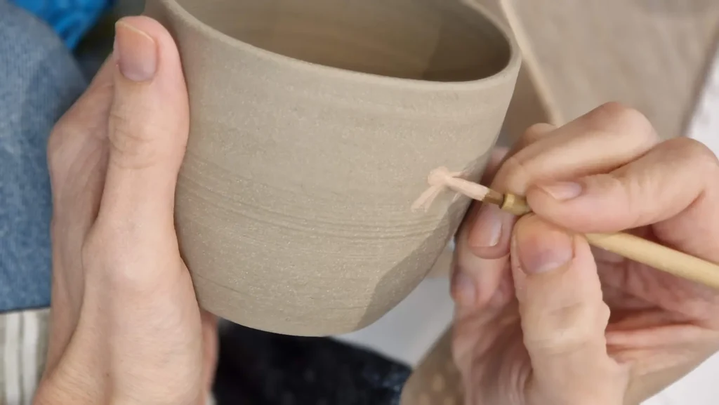 student painting tiger pattern on pottery